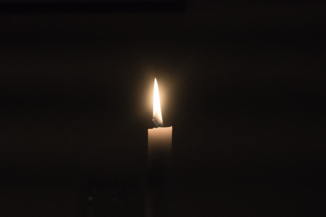 Lit candle in darkness